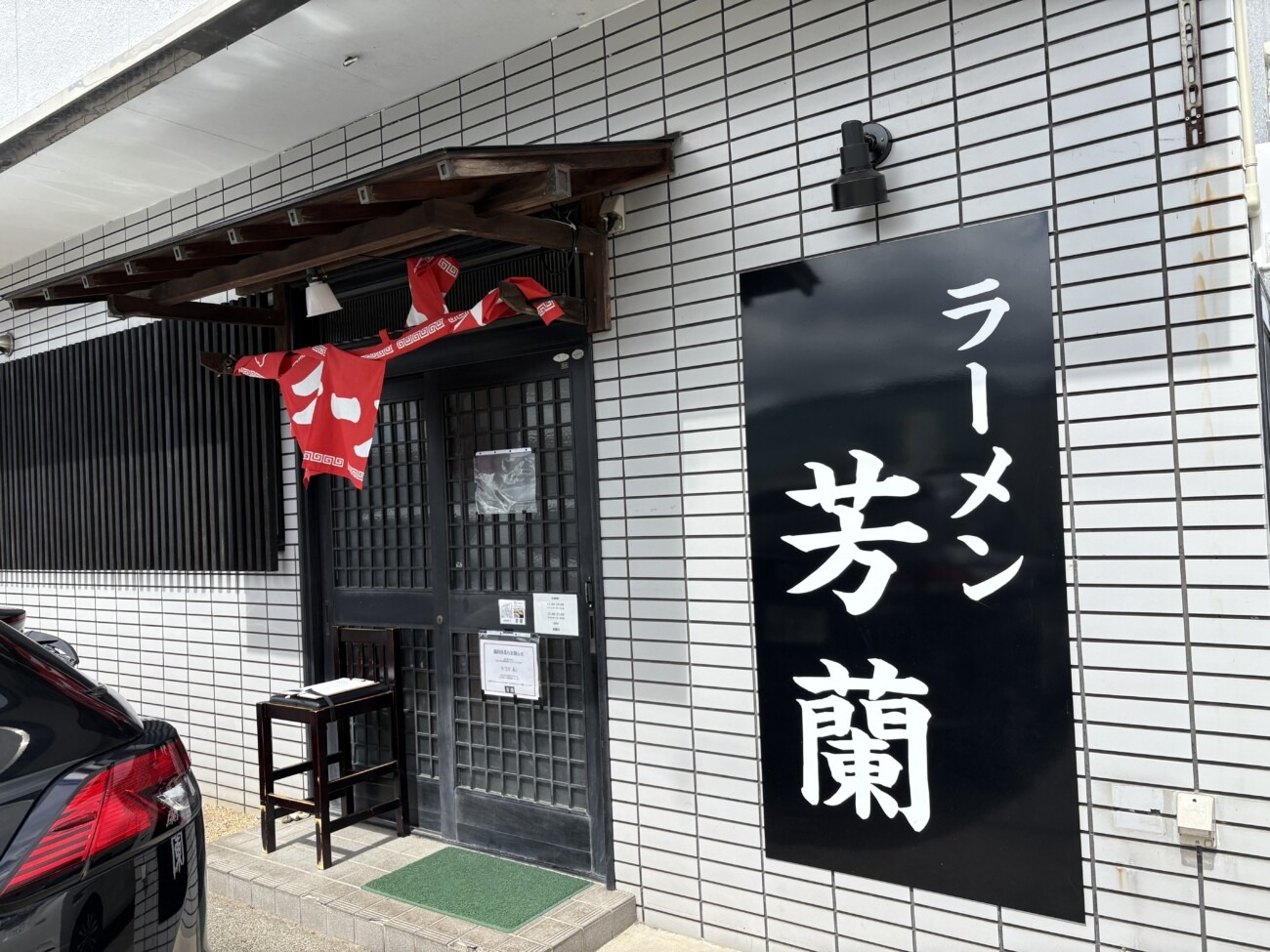 「ラーメン 芳蘭」の看板と店舗入り口、入口横に順番待ちの用紙